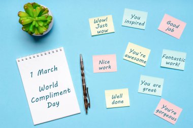 Happy World Compliment Day. Office desk with plant, notebook, pen and paper slips with compliments text for office worker such as GOOD JOB. Greeting card for world compliment day. Flat lay, top view. clipart