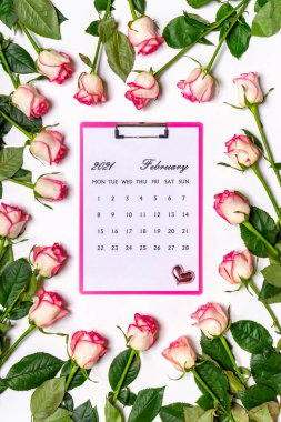 Sevgililer Günün kutlu olsun. Beyaz arka planda güzel pembe gül çiçeklerinden yapılmış çerçeve. Şubat 2021 takvimi panoda. Sevgililer Günü konsepti. Düz yatış, üst görünüm.