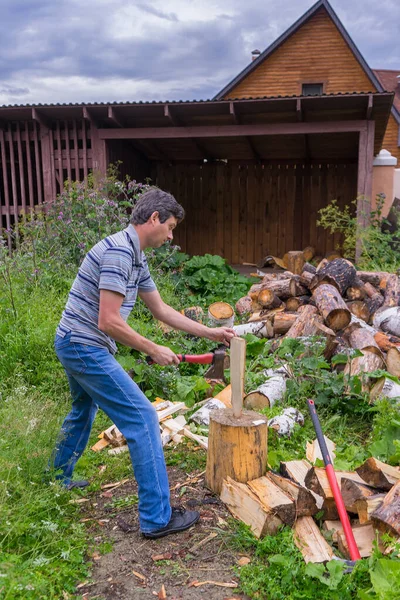 Przystojny Mężczyzna Średnim Wieku Rąbiący Drewno Siekierą Podwórku Wiejskiego Domu — Zdjęcie stockowe