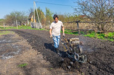 Wellingtons 'da ekicisi olan bir adam güneşli bir günde toprağı sürüyor. Toprak ekimi, toprak ekimi. Bahçede bahar işi. Bahçe konsepti.