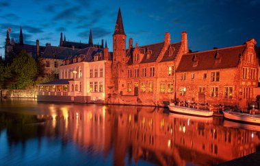BRUGES, BELGIUM - 20 Nisan 2013: Bruges, Belçika 'da bir kanal boyunca tarihi ortaçağ binaları.