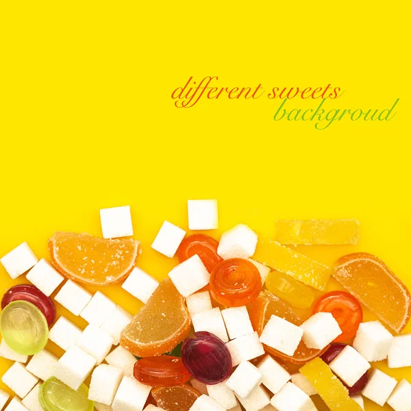 Caramelos coloridos, jaleas y azúcar sobre amarillo —  Fotos de Stock