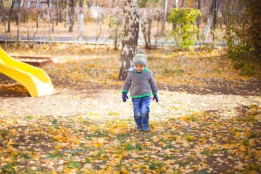 Parkta düşen yapraklarla oynayan çocuklar