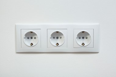Beyaz üçlü elektrik soketine ve duvar