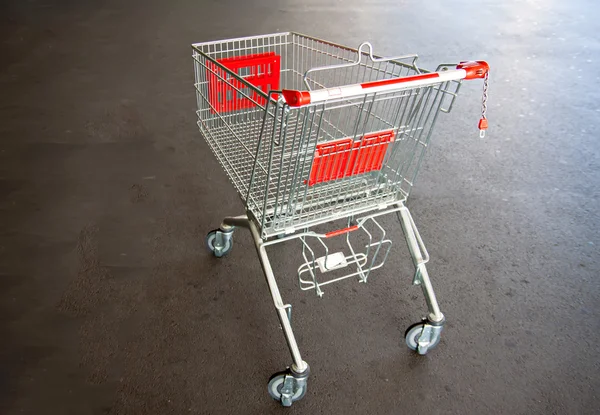 Metal trolley shopping basket at asphalt background — Stock Photo, Image