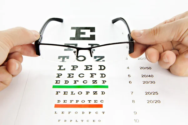 Óculos e gráfico de visão em fundo branco — Fotografia de Stock