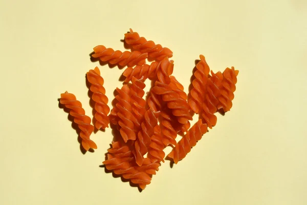 Close Dry Uncooked Orange Fusilli Pale Yellow Paper Background — Stock fotografie