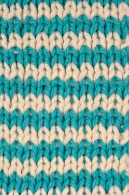 A macro close-up captures a chunky knitted textile pattern featuring horizontal teal and off-white chevron stripes