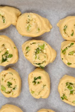 Tepeden çekilen fotoğrafta parmesan, sarımsak ve maydanozla dolu sayısız hamur rulosu var. Parşömen kağıdıyla kaplanmış bir fırın kağıdına dizilmiş.