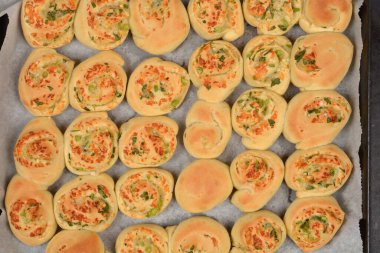  Genel bir bakış açısı, eritilmiş parmesan, sarımsak ve maydanozla dolu sayısız hamur rulosu gösteriyor.