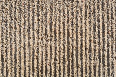 A full-frame close-up shows a rough, textured stucco wall with deep vertical grooves creating a striped pattern