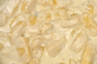 A full-frame, close-up view shows potato gnocchi coated in a rich, creamy Gorgonzola cheese sauce