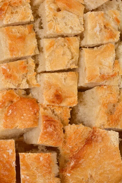  A close-up, full-frame shot of many small, square pieces of light-crusted bread, suitable for croutons, filling the entire image