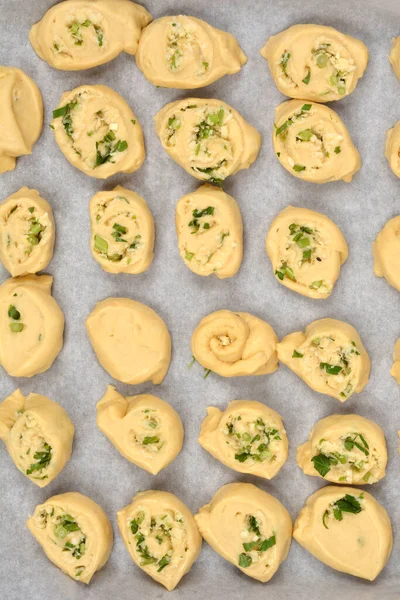 Tepeden çekilen fotoğrafta parmesan, sarımsak ve maydanozla dolu sayısız hamur rulosu var. Parşömen kağıdıyla kaplanmış bir fırın kağıdına dizilmiş.