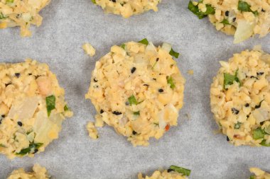 Daha çok doğranmış soya fasulyesi, soğan ve otlardan yapılan çiğ vejetaryen köfteleri, parşömen astarlı pişirme tepsisi üzerinde pişirilmeye hazırdır.