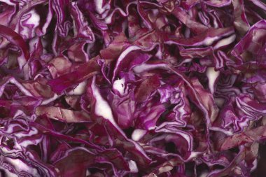 Tam kare, mor ve beyaz katmanları gösteren ince doğranmış kırmızı lahananın canlı arkaplan dokusunu yakalar.