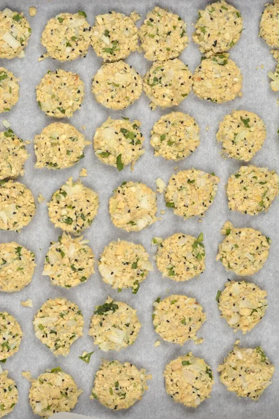 Daha çok doğranmış soya fasulyesi, soğan ve otlardan yapılan çiğ vejetaryen köfteleri, parşömen astarlı pişirme tepsisi üzerinde pişirilmeye hazırdır.