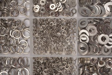 Çok bölmeli bir tepside çeşitli paslanmaz çelik yay yıkayıcıların çeşitli boyutlarını ve metalik dokusunu gösteren tepeden tırnağa, düzenli bir görüntüsü.