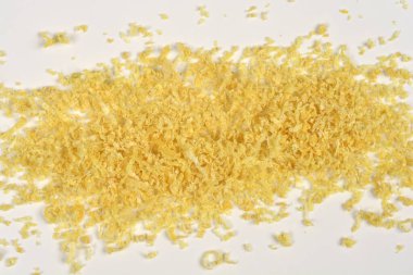 Güzel rendelenmiş, kurutulmuş sarı limon aromalı yatay bir şeritin yukarıdan görüntüsü. Temiz beyaz arka plana saçılmış.