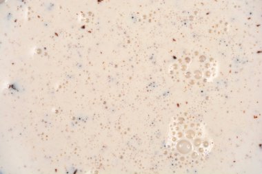 Küçük çikolata parçacıkları ve küçük yüzey kabarcıklarıyla karıştırılmış aşırı yakın çekim, tam kare tatlı krema sıvısı.