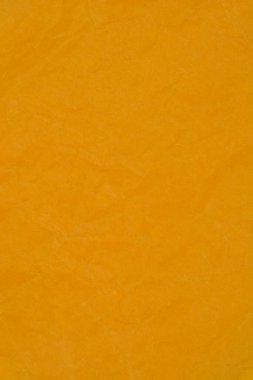 Sıcak, turuncu-sarı bir yüzeye dikey yakın çekim yumuşak kırışıklıkların belirgin, yoğun dokusu ve ezilmiş kağıda benzeyen rastgele kıvrımlar