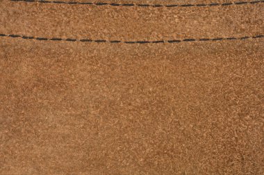 Tam kare makro çekim, kahverengi süet iç kısmının yumuşak, bez dokusunu yakalar ve üst tarafında siyah dikişler bulunur.