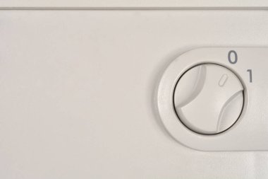 Yakın plan '0' ve '1' işaretli gri plastik bir döner anahtarı gösteriyor, açık bir şekilde '0' veya 'Kapalı' konumuna çevrilmiş soluk bir aygıt paneli