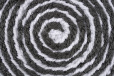 Koyu gri ve beyaz ipliğin dokusu sarmal, tam kare eş merkezli bir düzende düzenlenmiştir.