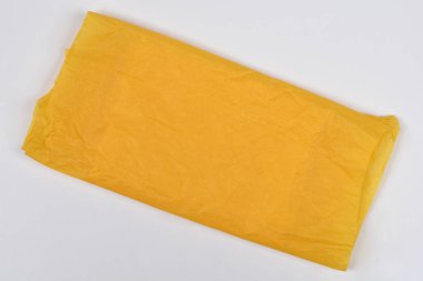 Dörtgen şeklinde pürüzsüz, buruşuk sarı mendil ya da ince ambalaj kağıdı düz beyaz arkaplan üzerine konur.