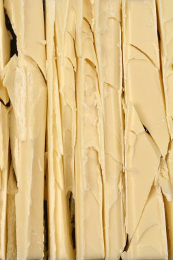Yakın plan çekimde, ince dilimlenmiş beyaz çikolata çubukları, pürüzlü kenarları ve kremsi sarı rengi vurguluyor.