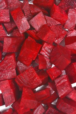 Görsel olarak karanlık, makro yakın çekim, yoğun, dikey bir düzenleme yakalar ham, taze kesilmiş pancar küpleri zengin, kırmızı bir renk ile