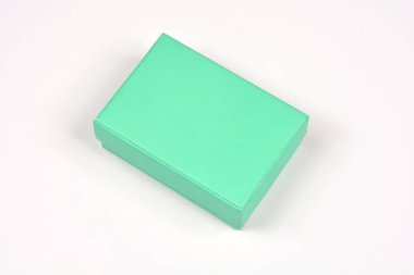 Nane yeşili renkte, küçük, kapalı, dikdörtgen bir hediye kutusu temiz beyaz bir arkaplanda açılıdır.