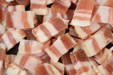 Detaylı, yakından çekilen bir görüntü çerçeveyi küçük, düzgün kesilmiş dikdörtgen küp ham, mermer pastırma veya domuz eti ile doldurur.