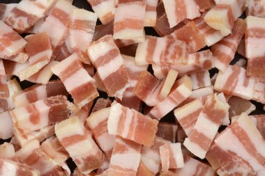 Yakın çekim, yüksek açı çerçeveyi küçük, düzensiz kesilmiş ham, mermer pastırma veya pancetta küpleriyle doldurur.