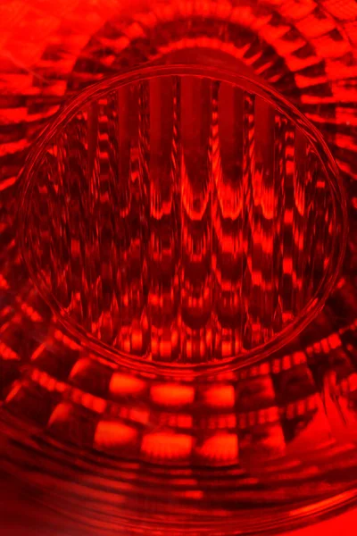Yakın çekim, soyut, makro çekim parlak kırmızı, desenli cam bir yüzey yakalar, muhtemelen bir arabanın fren lambası ya da yansıtıcısı.