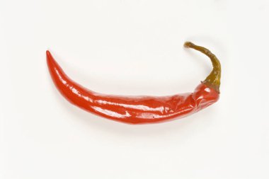 Tek, parlak, hafif kıvrımlı ve koyu yeşil saplı kırmızı biber turşusu düz beyaz arka planda yatay olarak yerleştirilir.