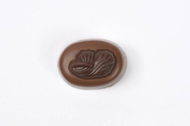 Kakao çekirdeği kabartmalı tek bir yuvarlak çikolatalı pralin sade beyaz arka plan üzerine kuruludur.