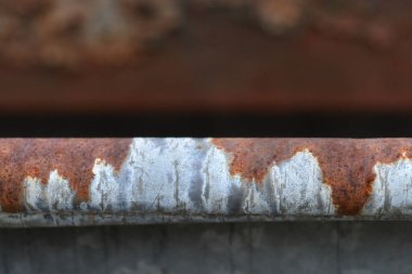 Yakın çekim yatay metal bir çubuk yakalar, gümüş rengi, çizik yüzeyi ve parlak turuncu pas parçaları arasındaki katı kontrastı ortaya çıkarır.