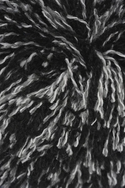 Yakın çekim, dikey çekim kalın yün veya akrilik ipliğin siyah beyaz veya gri liflerinin kabarık, tüylü dokusunu yakalar