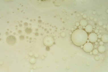 Krem renkli baloncuklardan oluşan soyut bir makro çekim ve sıvıdaki dokular eşsiz bir bulut sanat deseni oluşturuyor.