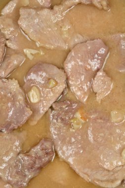 İnce domuz dilimleri lezzetli bir sosun içinde sarımsak parçalarıyla kaynatılır.
