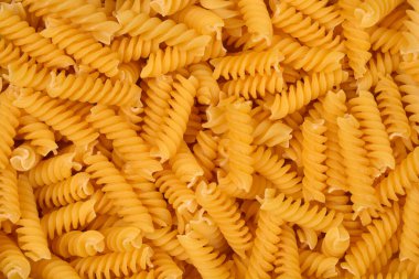 Çerçeveyi dolduran pek çok pişmemiş sarı fusilli makarna sarmalının yukarıdan aşağı yakın görüntüsü