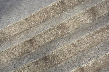 Yıpranmış beton merdivenlerin yüksek açılı çekimi, küçük taşlar ve doğal dokularla gri bir yüzeyi gösteriyor.