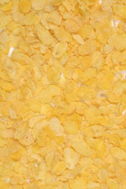 Altın mısır taneleri beyaz bir yüzey boyunca gevşek bir şekilde dağılır ve görünen beyaz boşluklarla dokulu bir arka plan oluşturur.