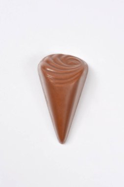 Tarafsız bir arkaplanda izole edilmiş girdap desenli sütlü çikolata şekeri şeklindeki tek bir üçgenin yukarıdan aşağı bakışı.