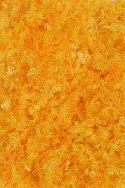 Taze rendelenmiş portakal kabuğunun tam kare makro görüntüsü canlı turuncu rengini ve parçalanmış dokusunu sergiliyor.