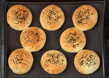 En üstteki görüntüde, fırından çıktıktan sonra üzerine siyah susam tohumları serpiştirilmiş sekiz altın sarısı yuvarlak çörek görülüyor.