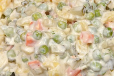 Yakın plan bir makro, Hırvat usulü kesilmiş sebze ve metal kasede kremalı mayonez ile yapılan Fransız salatasının dokusunu gösteriyor..