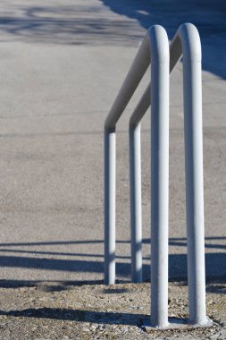 Beton merdivenlere döşenmiş uzun gölgeli beyaz metal bir tırabzanın yan görüntüsü.