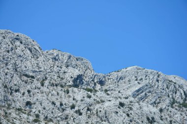 Peljesac yarımadasındaki Sveti Ilija dağının engebeli kireçtaşı yamaçları Hırvatistan 'daki açık mavi gökyüzüne sert bir şekilde karşı yükseliyor